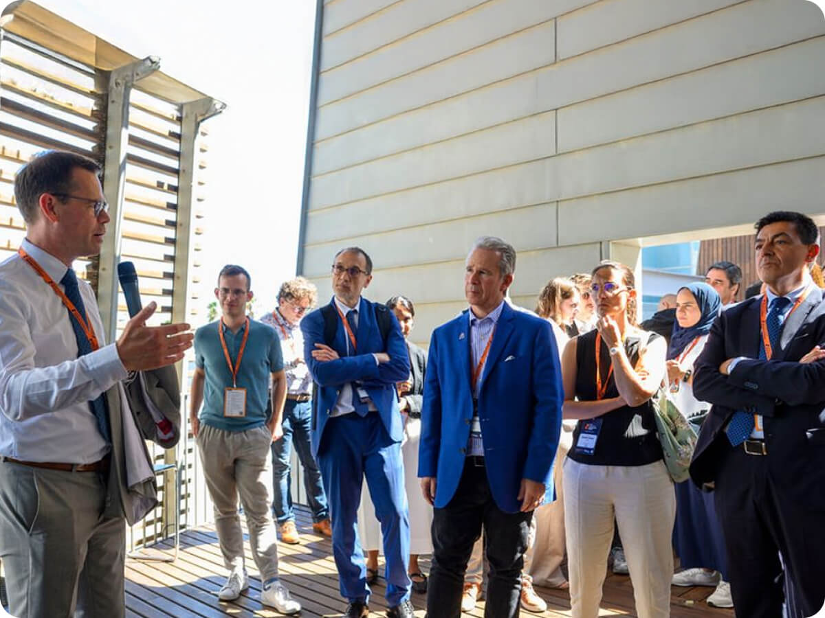 Man with microphone presents to group stand around him
